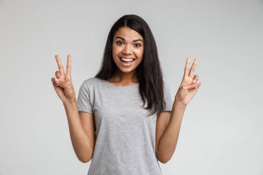 Çekici Afrikalı Amerikalı kadın, günlük kıyafetler giyip gri arka planda tek başına duruyor.