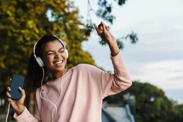 Imagen Una Niña Afroamericana Sonriente Usando Teléfono Móvil Auriculares Mientras —  Fotos de Stock