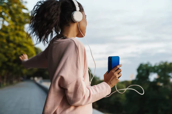 Imagen Una Niña Afroamericana Sonriente Usando Teléfono Móvil Auriculares Mientras —  Fotos de Stock