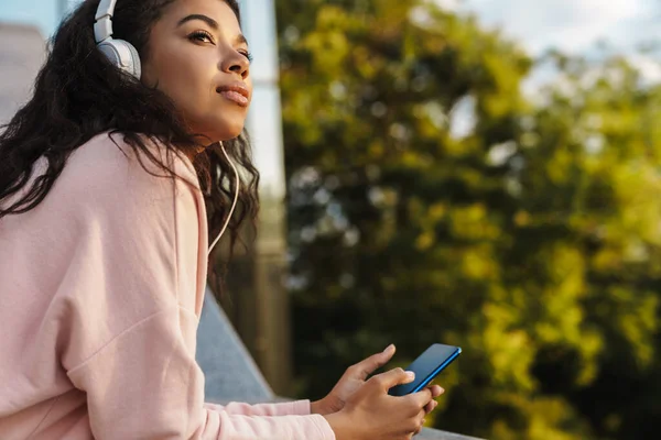 Kép Elégedett Afro Amerikai Lány Aki Mobiltelefont Fejhallgatót Használ Séta — Stock Fotó