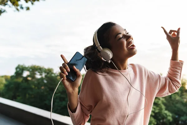 Imagen Una Niña Afroamericana Sonriente Usando Teléfono Móvil Auriculares Mientras —  Fotos de Stock