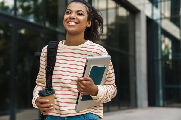 Imagen Alegre Chica Afroamericana Bebiendo Café Mientras Camina Con Portátil — Foto de Stock