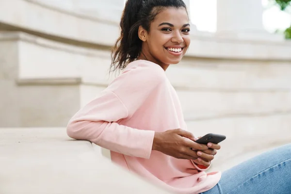 Imagen Niña Afroamericana Sonriente Usando Teléfono Celular Mientras Está Sentada — Foto de Stock