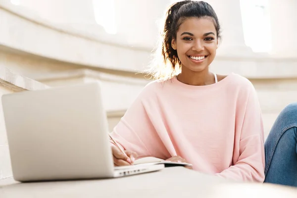 Imagen Alegre Estudiante Afroamericana Haciendo Tarea Con Portátil Mientras Está — Foto de Stock