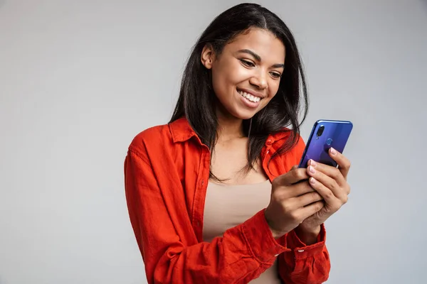 Улыбающаяся Молодая Африканка Отправляющая Смс Мобильный Телефон Изолированная Сером Фоне — стоковое фото