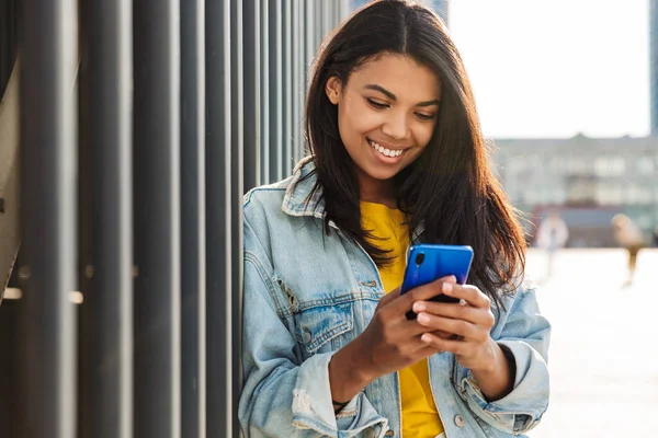 Imagen Alegre Mujer Afroamericana Sonriendo Usando Teléfono Inteligente Mientras Está — Foto de Stock