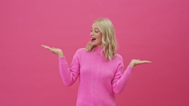 Усміхнена Блондинка Рожевому Светрі Тримає Вільний Простір Руках Долоні Стоять — стокове відео