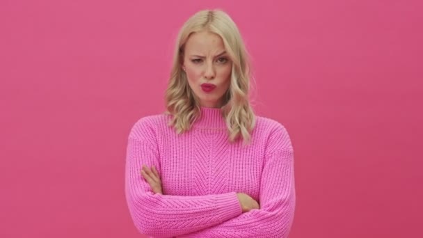Недовольная Блондинка Розовом Свитере Скрещивает Руки Стоя Изоляции Розовом Фоне — стоковое видео