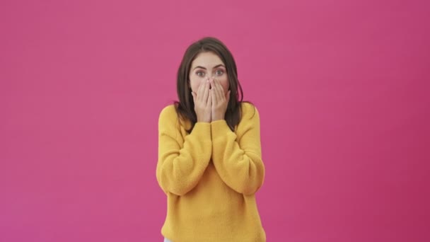 一位穿着黄色毛衣 惊慌失措的女人站在粉色背景下 张开嘴 — 图库视频影像