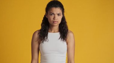 Kendine güvenen genç bir kadın sarı arka planda izole bir şekilde duruyor.