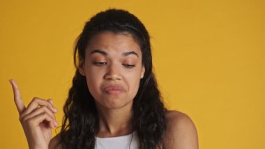 Mutlu genç bir kadının yakın plan görüntüsü sarı arka planda izole edilmiş bir şeyin hayalini kuruyor.