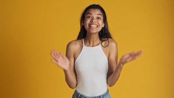 Здивована Молода Жінка Плескає Руками Стоячи Ізольовано Жовтому Тлі — стокове відео