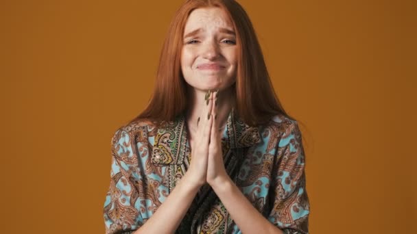 茶色の背景の上に隔離された立って祈りのジェスチャーをしている間感情的な若い女性は何かを求めている — ストック動画
