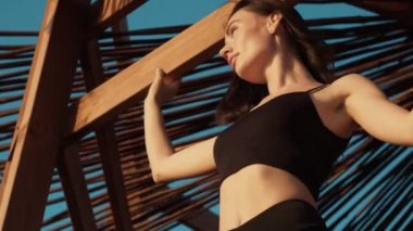 Genç ve sportif bir kadının alttaki görüntüsü sabahın köründe sahildeki oyukta duruyor.