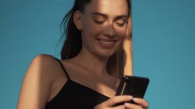 Mutlu genç bir kadının alttaki görüntüsü sabahları sahilde dururken akıllı telefonunu kullanıyor.