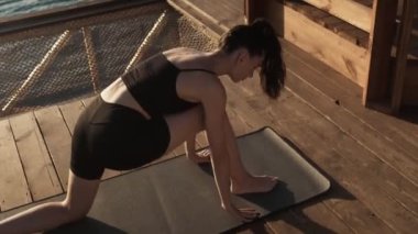 Sportif genç bir kadın sabahları plajda yoga egzersizleri yapıyor.