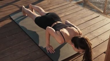 Genç ve güzel bir kadın yoga egzersizleri yapıyor. Sabahları onu kumsalda geriyor.