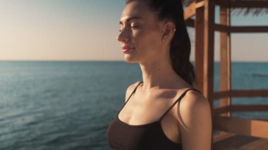 Genç ve güzel bir kadın sabah deniz kenarında güneşleniyor.