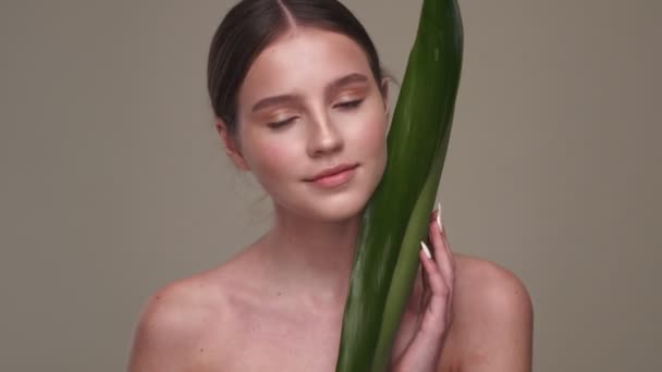 Νεαρή Θετική Γυναίκα Υγιές Δέρμα Που Ποζάρει Φύλλα Απομονωμένα Γκρι — Αρχείο Βίντεο