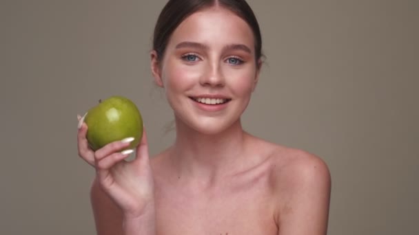 Νεαρό Χαρούμενο Κορίτσι Κρατώντας Πράσινο Μήλο Απομονώνονται Πάνω Από Γκρι — Αρχείο Βίντεο