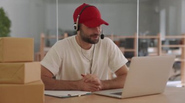 Ofisteki genç mutlu posta müdürü, paket kutularının yanında müşteriyle konuşuyor.