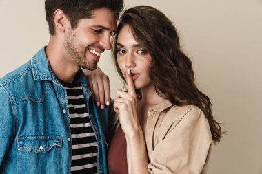 Bej arka planda izole edilmiş güzel bir çiftin kucaklaşması ve gülümsemesi.
