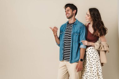 Neşeli, güzel bir çiftin beyaz arka planda izole edilmiş bir şekilde parmakla gösterip gülmesi.