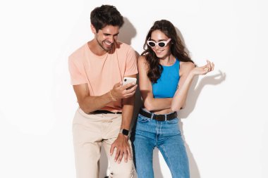 Beyaz arka planda izole edilmiş cep telefonuyla gülen neşeli çiftin görüntüsü
