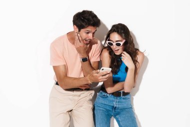 Beyaz arka planda izole edilmiş cep telefonu kullanırken şaşırdıklarını ifade eden çekici bir çift görüntüsü