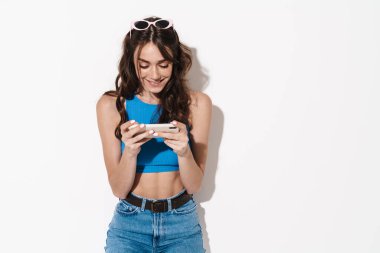 Mutlu, güzel bir kadının beyaz arka planda izole bir şekilde cep telefonu ve gülümsemesi.