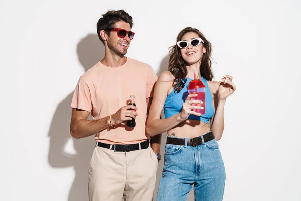 白地に隔離された飲料を飲みながら笑う陽気な美しいカップルのイメージ — ストック写真