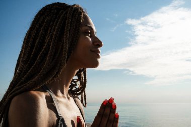 Spor giyimli sakin Afro-Amerikalı bir kız dışarıda beton gezinti güvertesinde oturuyor.