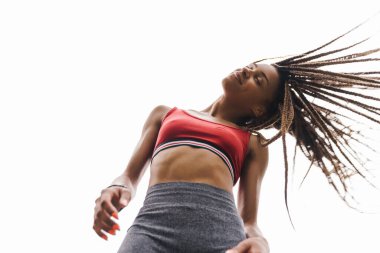 Arka planda mavi gökyüzü ile poz veren fit ve genç bir Afrikalı spor kadınının alt görünümü