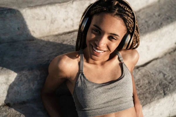 Image Happy African American Girl Using Headphones While Sitting Concrete — Stock Photo, Image