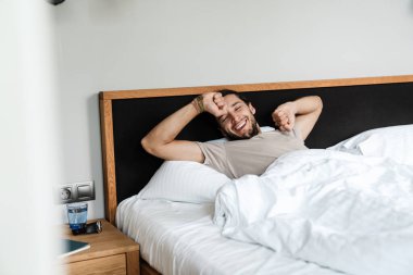 Mutlu genç adam sabah uyandığında evde yatağında