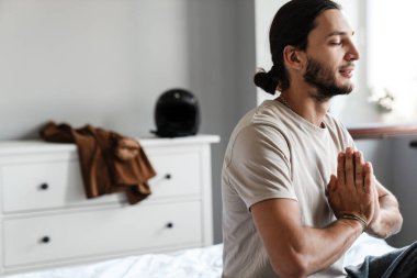 Genç adam sabahları yatak odasında meditasyon yapıyor.