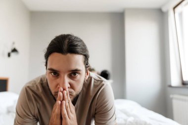 Depresyondaki genç adam evde yatakta oturuyor.