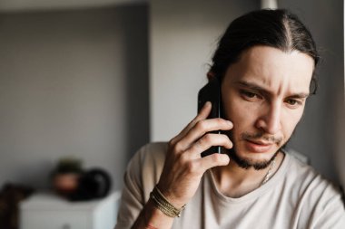 Kapalı alanda cep telefonuyla konuşan endişeli bir adama yaklaş.