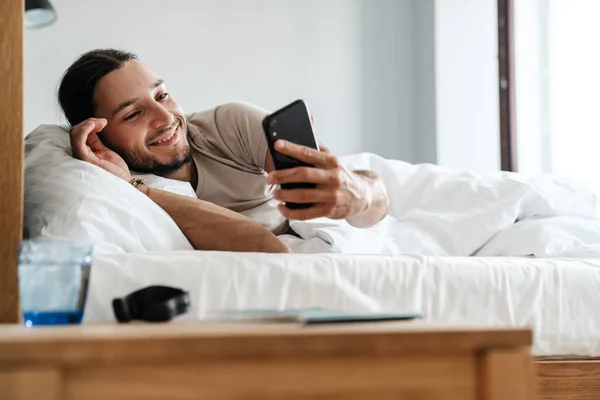 Sonriente Joven Usando Teléfono Móvil Mientras Está Acostado Cama Por —  Fotos de Stock