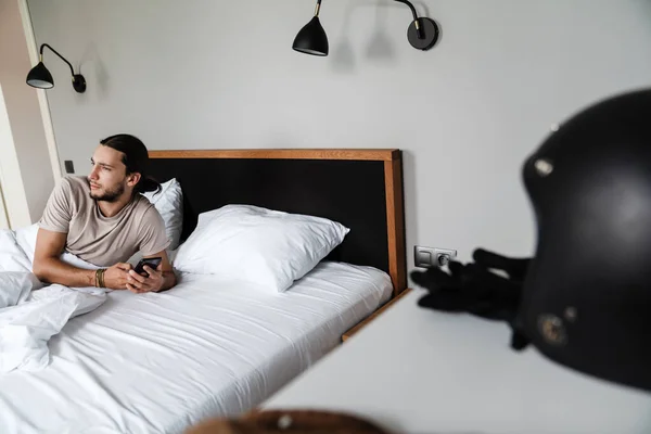 Lächelnder Junger Mann Mit Handy Während Morgens Bett Liegt — Stockfoto