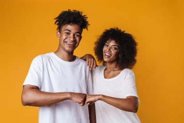 Mutlu Afro-Amerikan çiftin görüntüsü gülümseyen ve sarı duvarın üzerinde yumruk tokuşturan