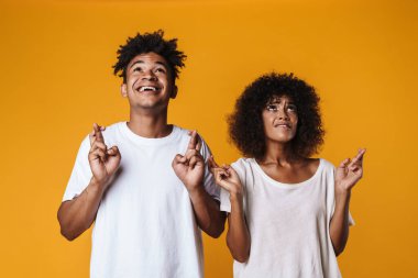 Genç Afro-Amerikan çiftin görüntüsü parmakları çapraz sarı duvarın üzerinden yukarı bakıyor.