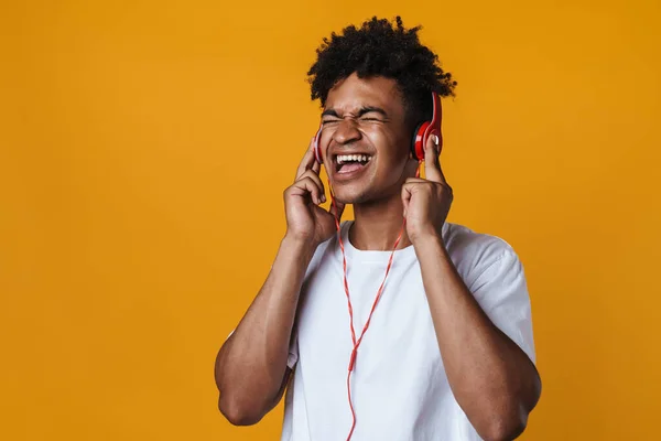 興奮したアフリカ系アメリカ人の男のイメージヘッドフォンで音楽を聞いて 黄色の壁に隔離された歌 — ストック写真