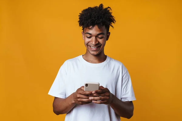 一个快乐的非洲裔美国人面带微笑 用手机隔着黄墙的照片 — 图库照片