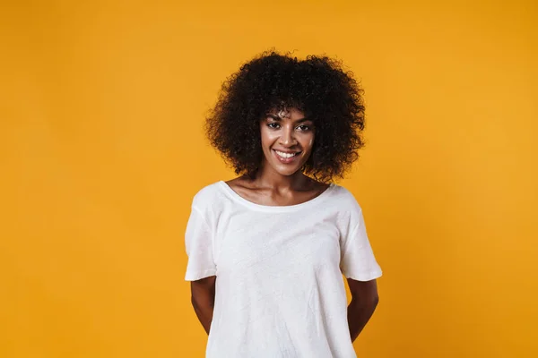 Image of happy african american girl smiling and looking at camera isolated over yellow wall