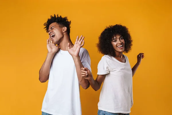 图为一对快乐的非洲裔美国夫妇在黄墙上独自唱歌跳舞的情景 — 图库照片