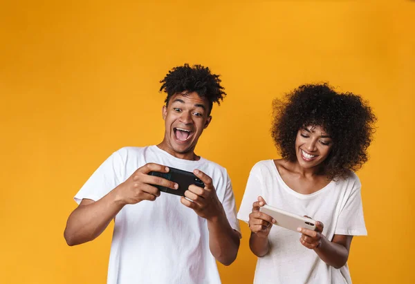 黄色の背景に隔離された携帯電話でオンラインゲームをプレイ興奮アフリカ系アメリカ人の写真 — ストック写真