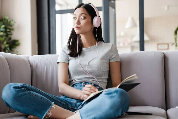 Immagine Pensare Asiatico Studente Ragazza Cuffie Annotando Note Mentre Seduto — Foto Stock