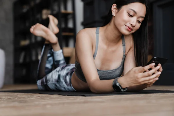 Imagen Alegre Chica Asiática Ropa Deportiva Usando Teléfono Móvil Mientras — Foto de Stock