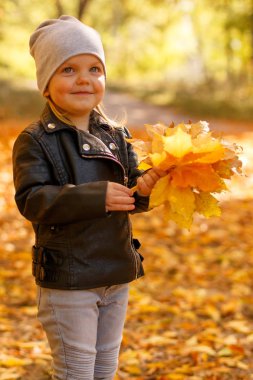 Sonbahar parkta oynarken bir deri ceket, küçük kız.
